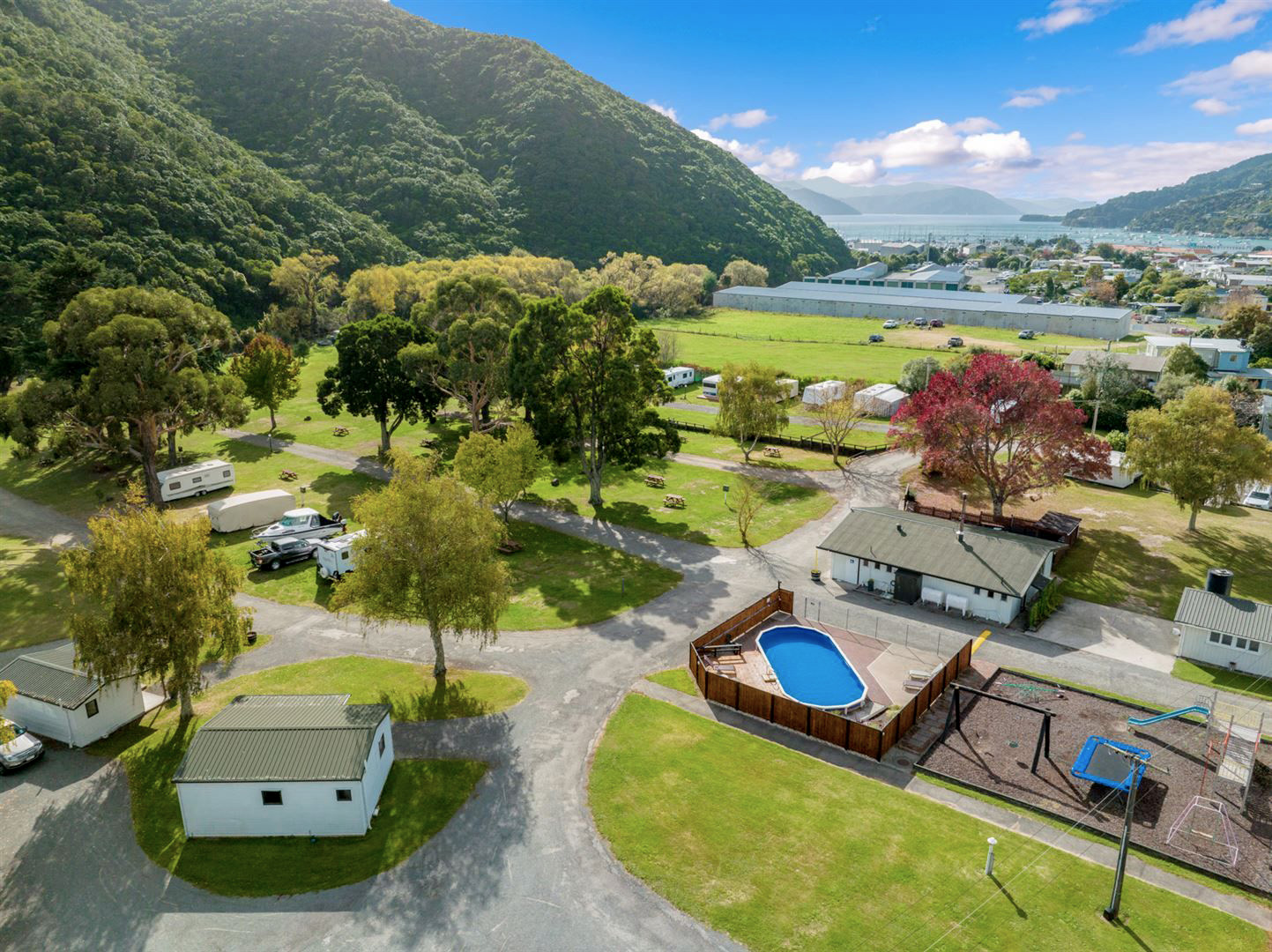 Picton TOP 10 Holiday Park – conveniently close to the Marlborough Sounds Drone shot of Picton TOP 10 Holiday Park with Queen Charlotte Sound in the background.